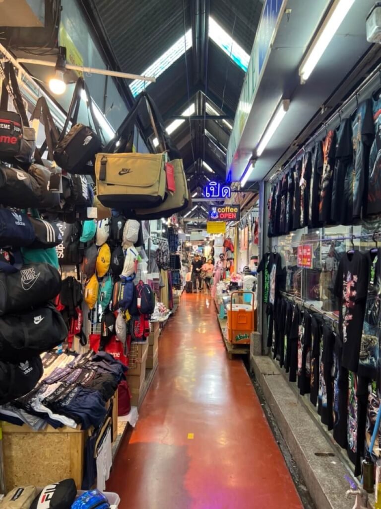 Allée remplie de vêtements et accessoires au marché Chatuchak, un incontournable pour les amateurs de shopping.