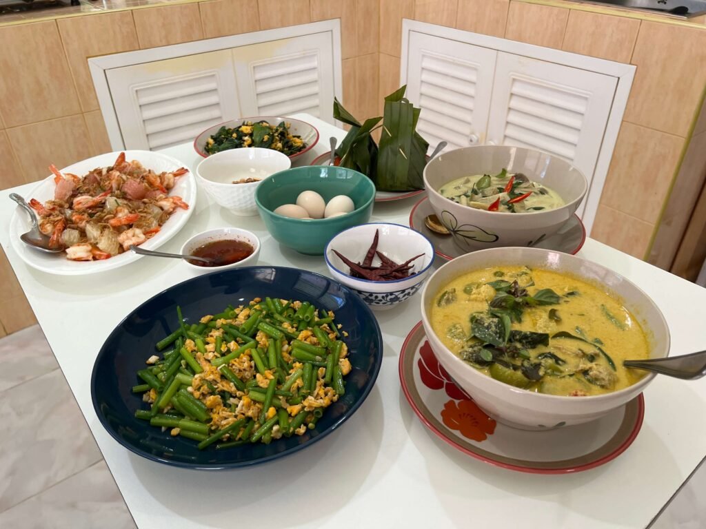 Table remplie de plats thaïlandais traditionnels, comprenant du curry vert, des légumes sautés et des spécialités locales. Planifier un itinéraire pour un premier voyage en Thaïlande