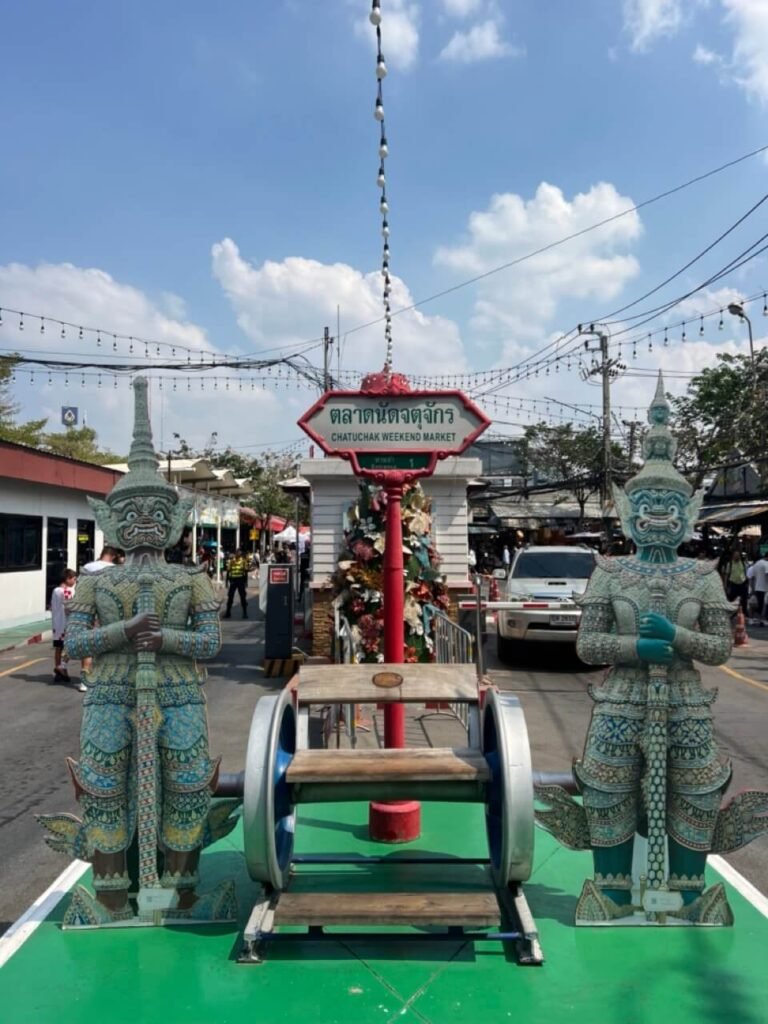 Entrée principale du marché Chatuchak avec des sculptures colorées représentant des gardiens traditionnels thaïlandais.