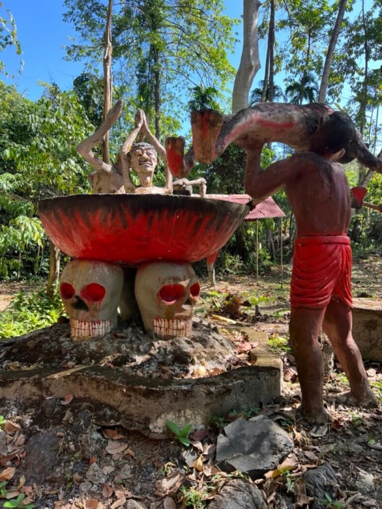 Statues bouddhistes au cœur de la nature dans un temple du sud de la Thaïlande, ornées d'offrandes spirituelles.